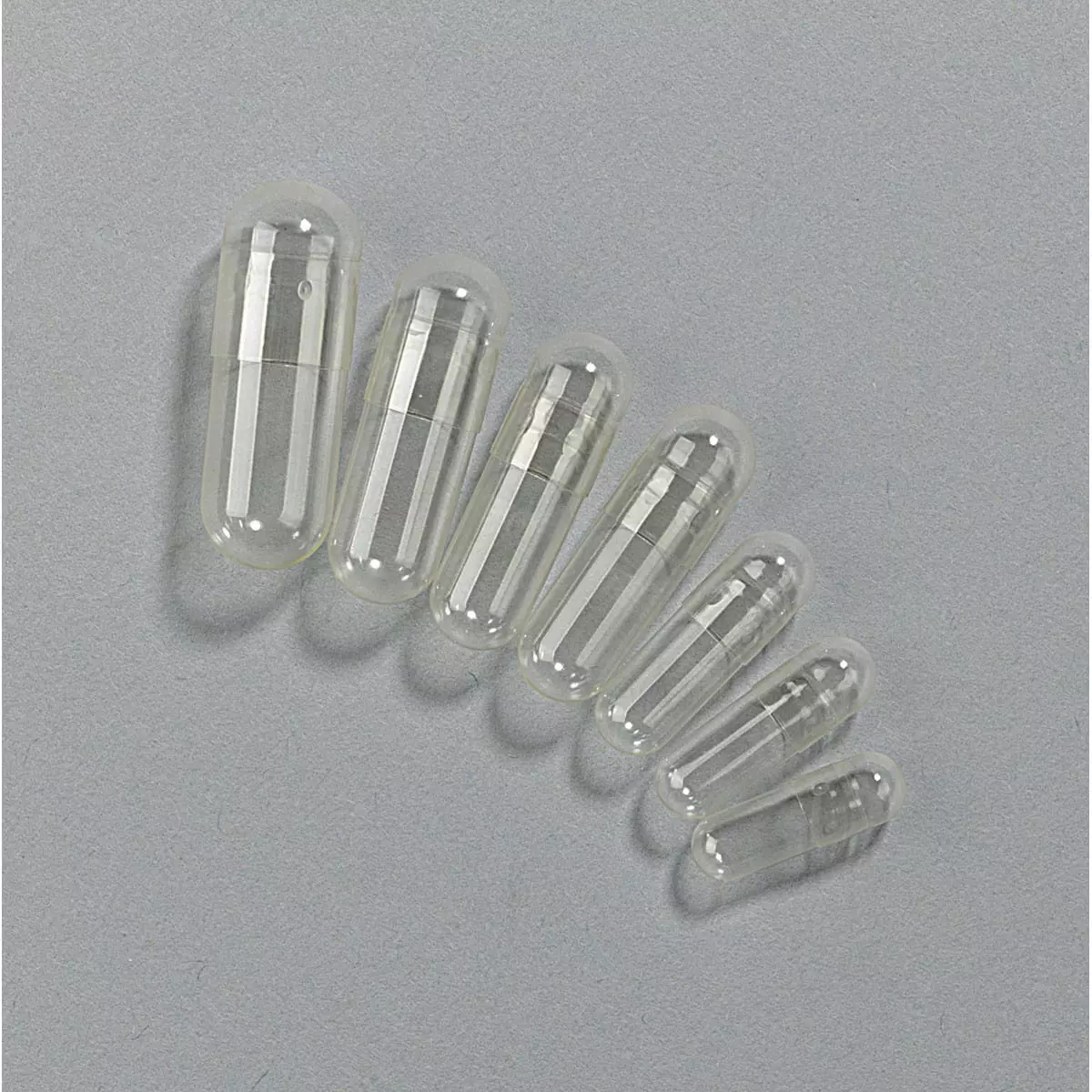 Clear empty pharmaceutical capsules arranged in graduated sizes